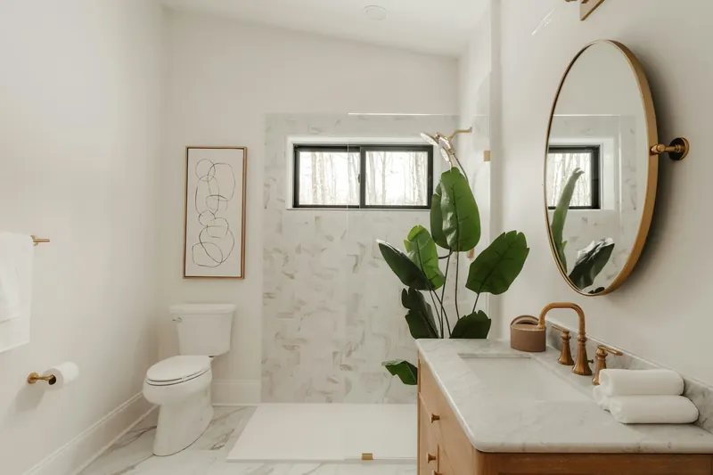 Mermer duvar, pirinç armatür ve oval aynalı banyo